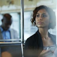 Woman of color in business attire sitting on public transportation