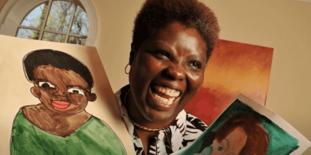 Disability advocate and Black woman Lois Curtis holding two paintings and smiling