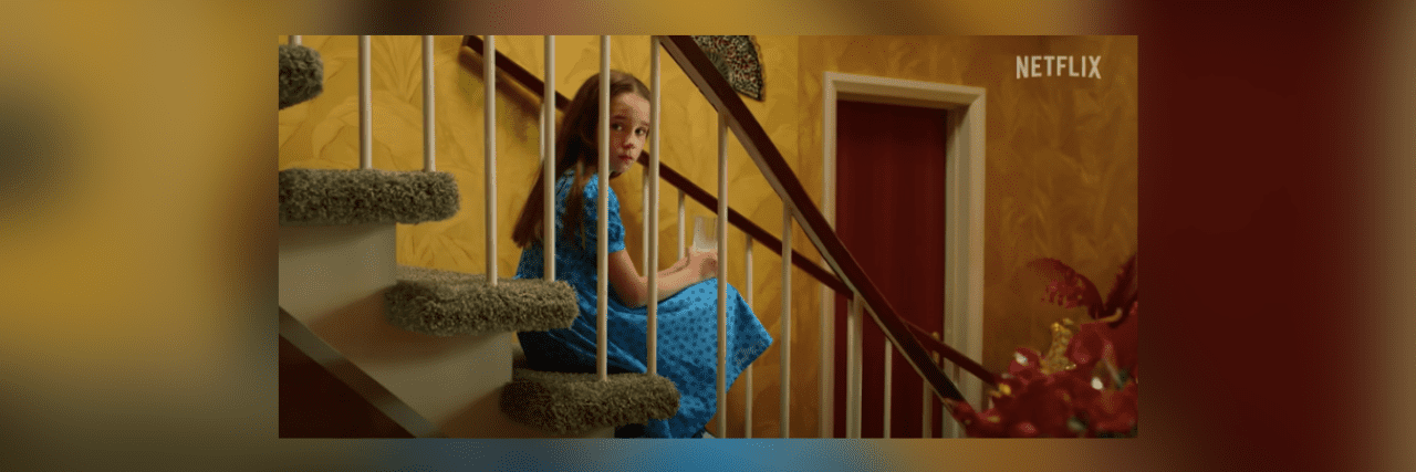 Image of Matilda from "Matilda the Musical" sitting on stairs behind railing