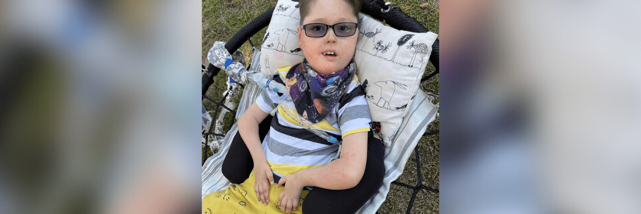 Contributor's son, smiling and wearing sunglasses while laying on cushion on swing