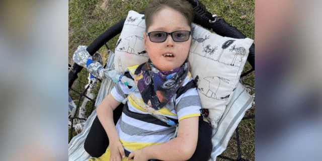 The Hardest Part of Parenting a Child With a Rare Disorder Contributor's son, smiling and wearing sunglasses while laying on cushion on swing