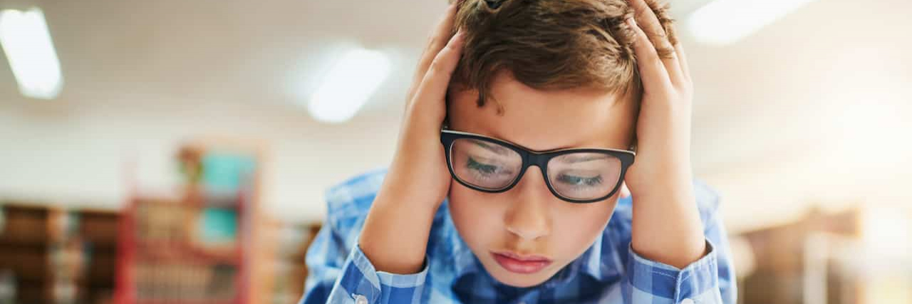 How Kids With ADHD Are Misunderstood Young boy looking stressed out while working in class at school