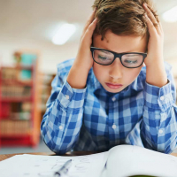 Young boy looking stressed out while working in class at school