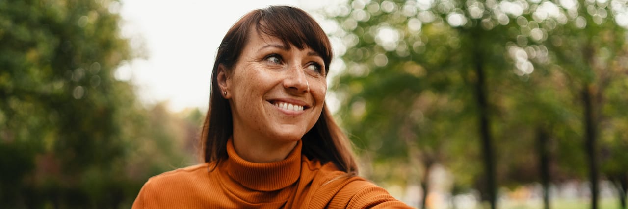 Woman sitting on bench and smiling while looking to the side