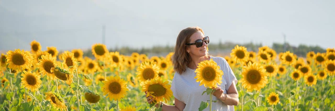 Woman wearing sunglasses in sunflower field