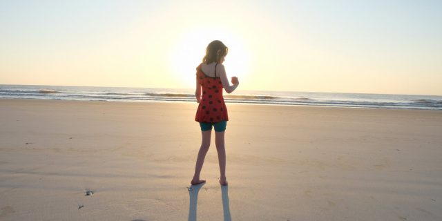 Silhouette of child standing on beach at sunset