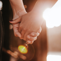 Close up on hands held together with sun streaming behind them