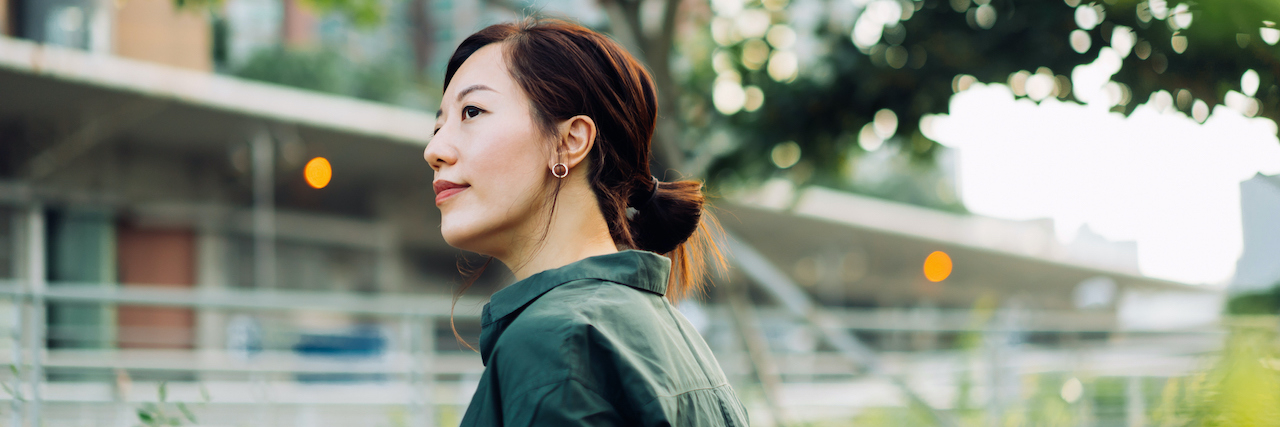 Is Dissociative Identity Disorder the Ultimate Survival Skill? Asian woman outside with coffee in an urban park area