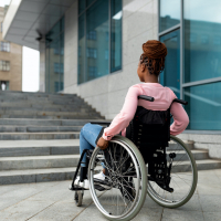 Black woman in wheelchair in front of stairs