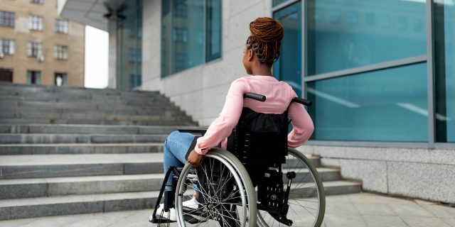 Black woman in wheelchair in front of stairs