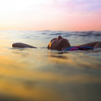 Woman floating in calm water at sunset