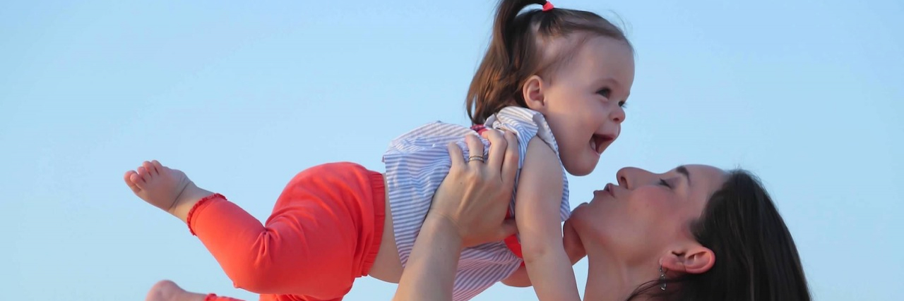 Contributor playfully holding her young daughter up in the air