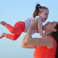 Contributor playfully holding her young daughter up in the air