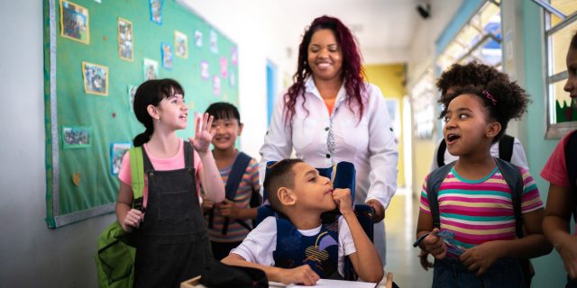 5 Tips for Parents Advocating for Inclusion  Teacher and students walking in corridor at school including student with a disability
