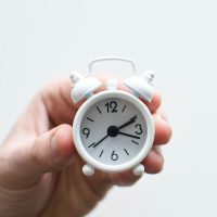 Person's hand holding tiny alarm clock