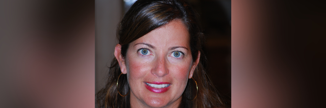 Contributor, a woman with long brown hair and blue eyes, smiling and looking forwards