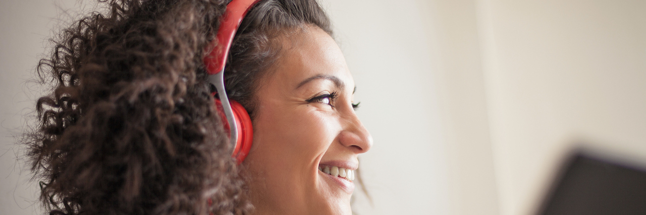 Best Podcasts for Anxiety and Mental Health Woman wearing red headphones and holding tablet