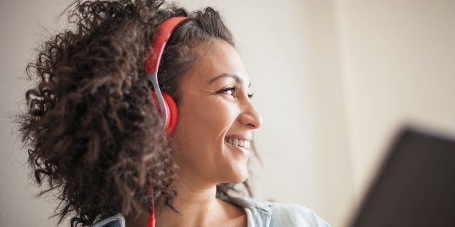 Woman wearing red headphones and holding tablet