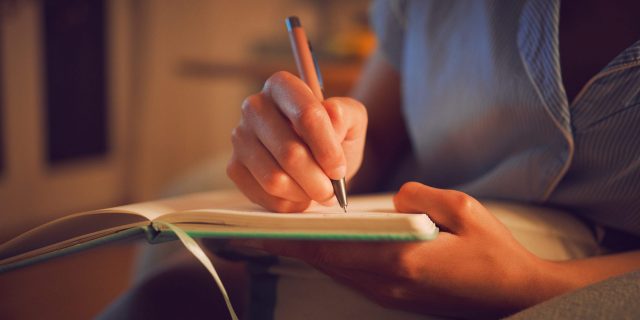 Close up of woman making notes in a journal