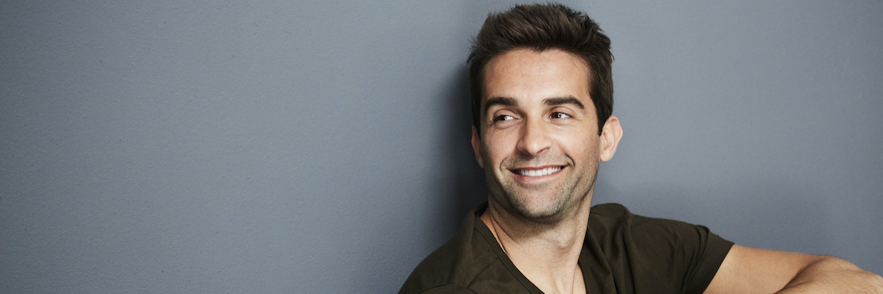 Narcissist Gaslighting: Top Signs to Look For Relaxed man sitting against a wall smiling and looking away