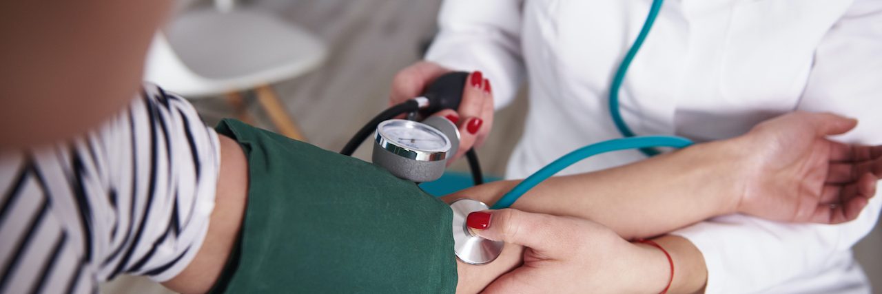 Close up of a medical professional taking a woman's blood pressure