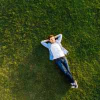 Young man laying on grass with arms behind his head