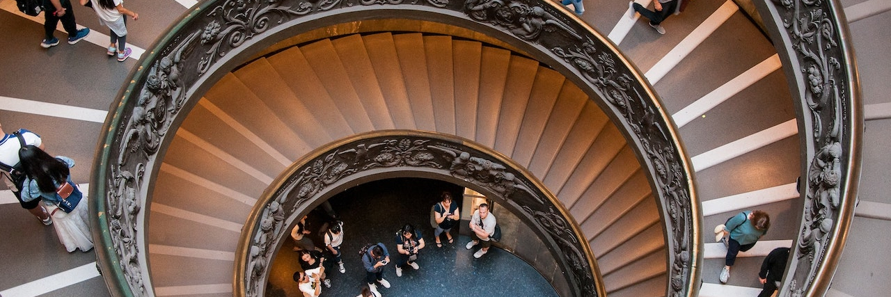 Image from above of large spiral staircase with people walking down it