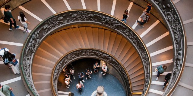 Image from above of large spiral staircase with people walking down it
