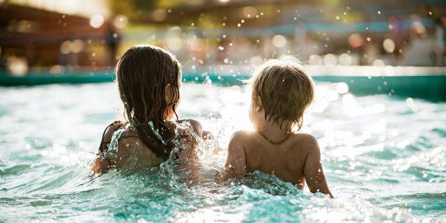 Rear view of young boy and girl splashing in a pool