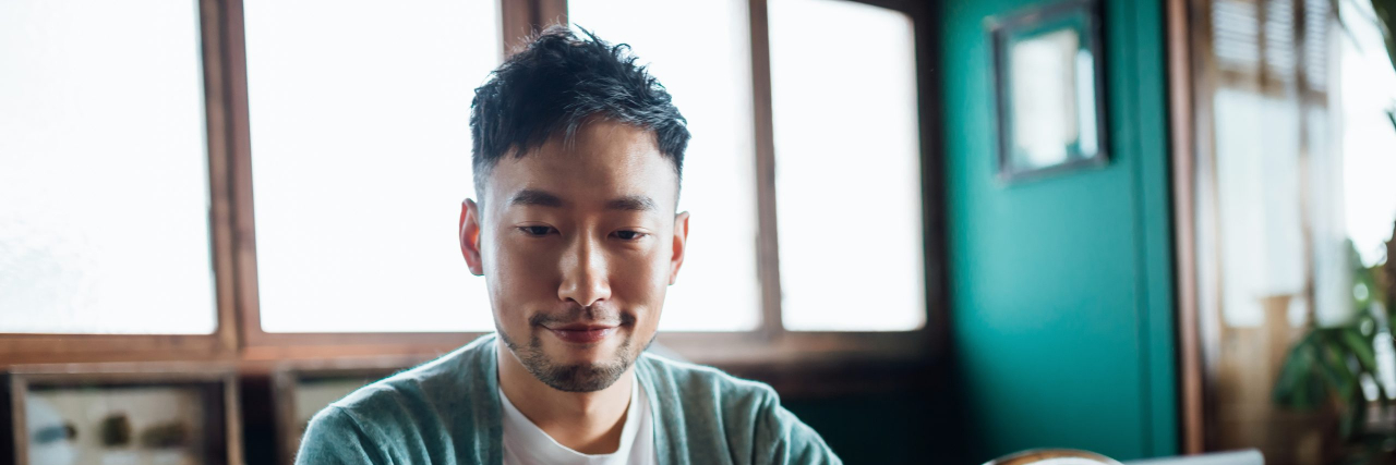 Diagnosed with Ulcerative Colitis? Follow These Social Media Accounts Confident young Asian man looking at smartphone while working on laptop