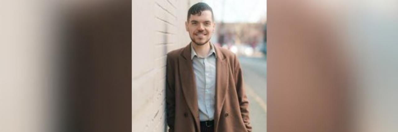 Dominic Kelly standing next to a brick wall