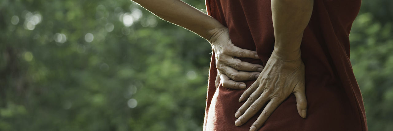 My Experience With a Spinal Stimulator for Chronic Back Pain Close up of woman holding her back with her hands outside