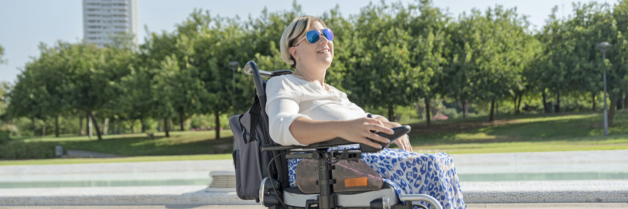 Woman using power wheelchair outside in urban park