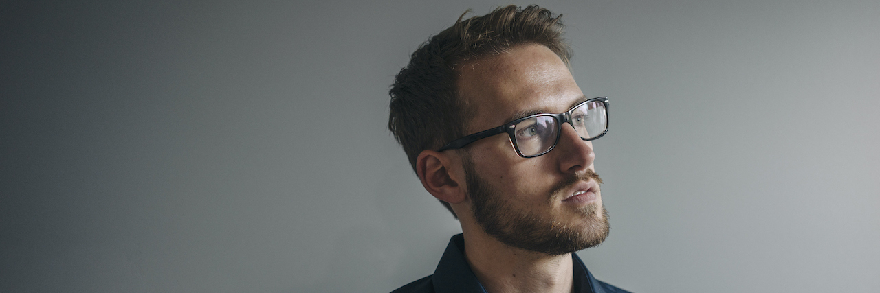 Why I Share My Story of Abuse Man with glasses looking thoughtful