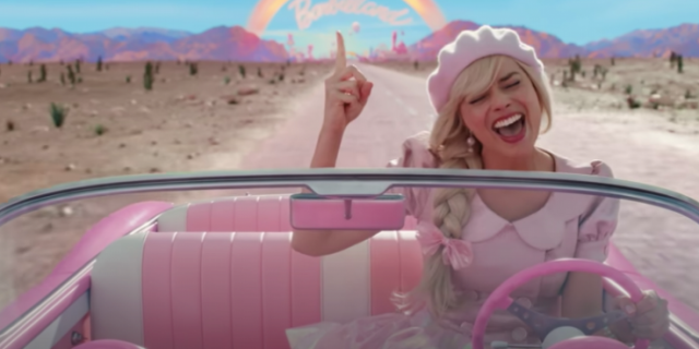 Image from "Barbie" movie of Barbie singing and driving away from Barbieland in pink convertible