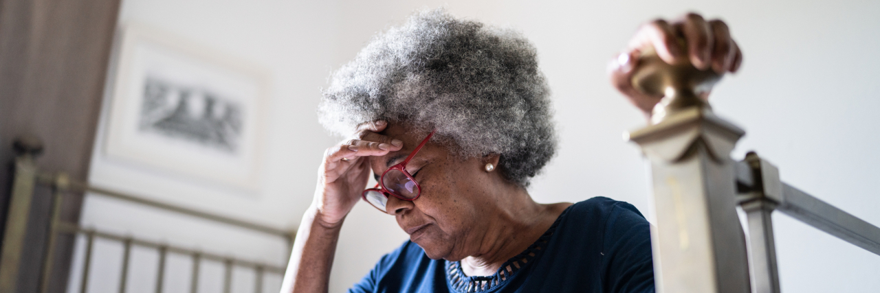 39 Myths About Alzheimer's You Should Stop Believing Now Senior woman with headache sitting in the bed at home