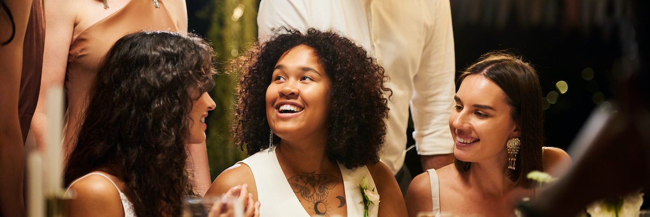 11 Tips on Making It to the Ceremony: A Wedding Party Guide for Those With Chronic Illness Diverse group sitting at a table during a wedding reception