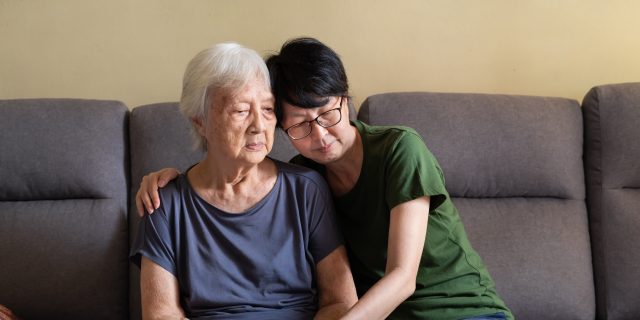 Woman spending quality time with her depressed elderly mother at home.