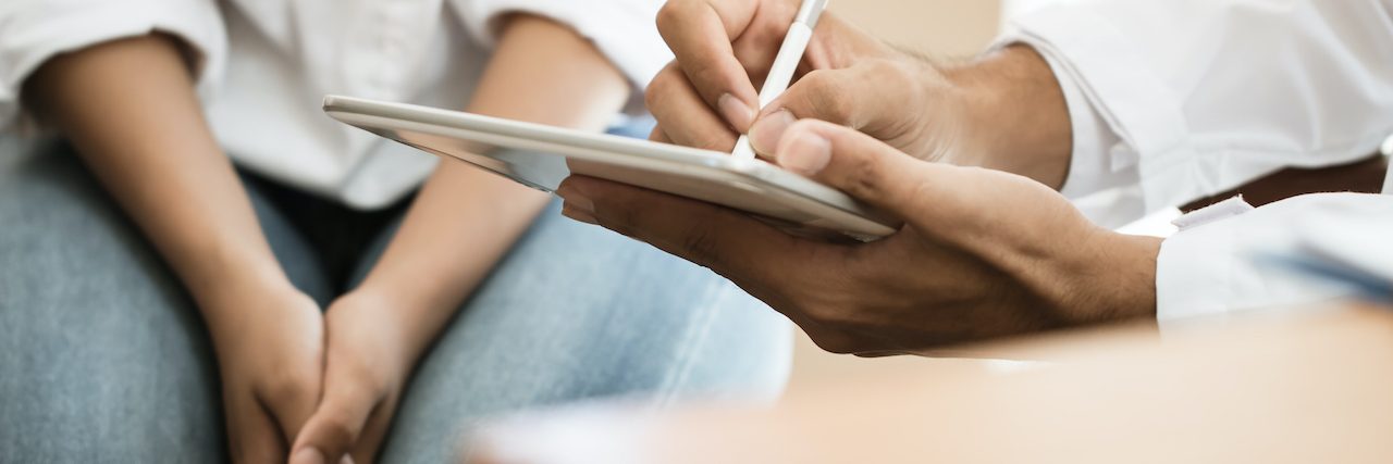 Who Prescribes ADHD Meds After an ADHD Diagnosis Close up of medical professional writing on tablet with patient next to them
