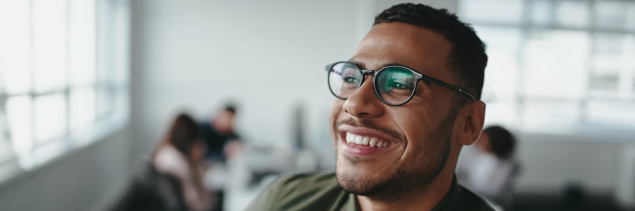 Person of color wearing glasses and smiling in office setting