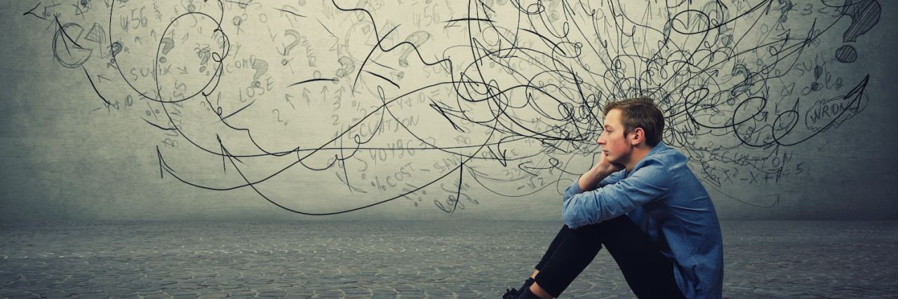 Can You Have OCD and ADHD at the Same Time? Man sitting on the floor with drawings of arrows, question marks and scribbles representing mental distress