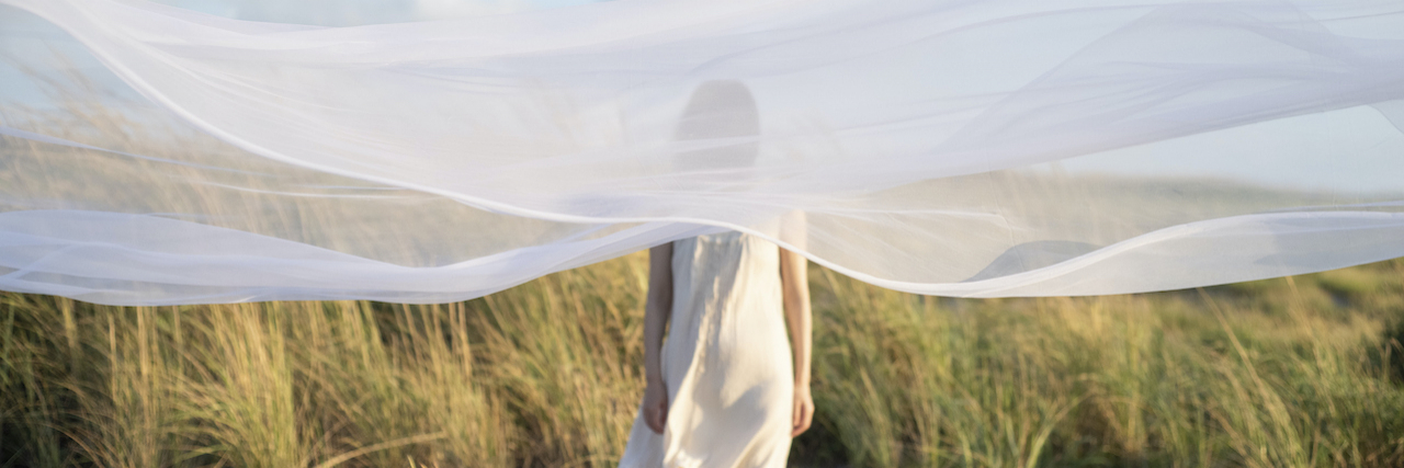Woman standing behind translucent veil in nature