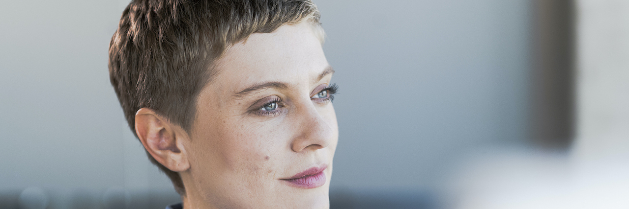 The Problem With the Standard of Care After Breast Cancer Treatment Ends Woman with short brown hair looking into the distance