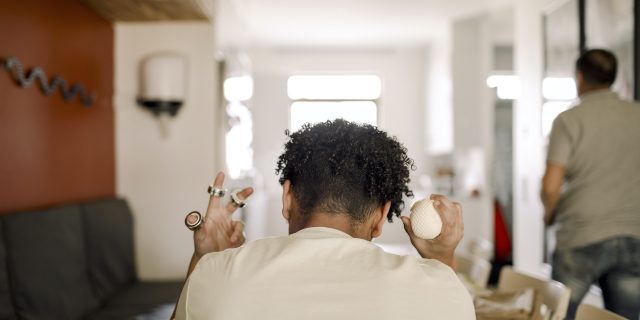 Rear view of person sitting at table at home holding ring fidgets on fingers and stress ball in other hand