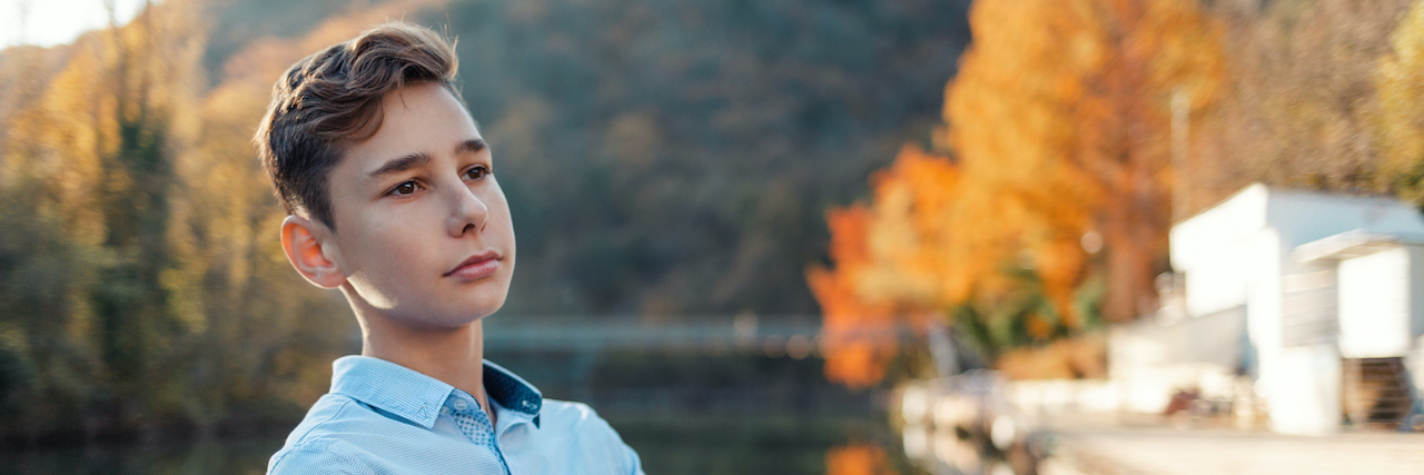 How to Help a Child With ADHD Without Medication Teen boy standing against a background of river and trees with his arms crossed