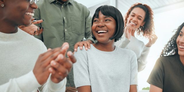 What Is Sobriety? Shot of an attractive young woman sitting while her support group celebrate her success