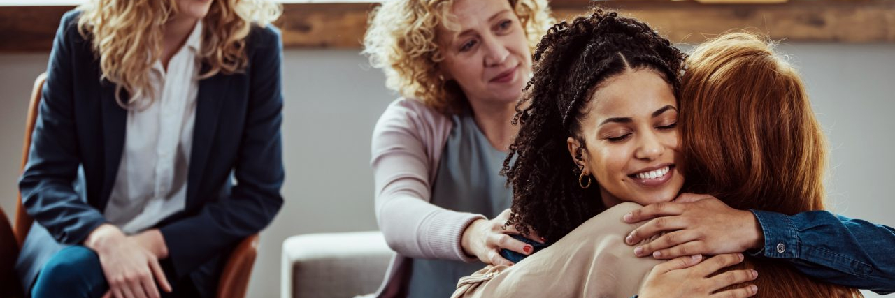 How to Create a Relapse Prevention Plan Caring female counselor hugs a female patient during a group therapy session.