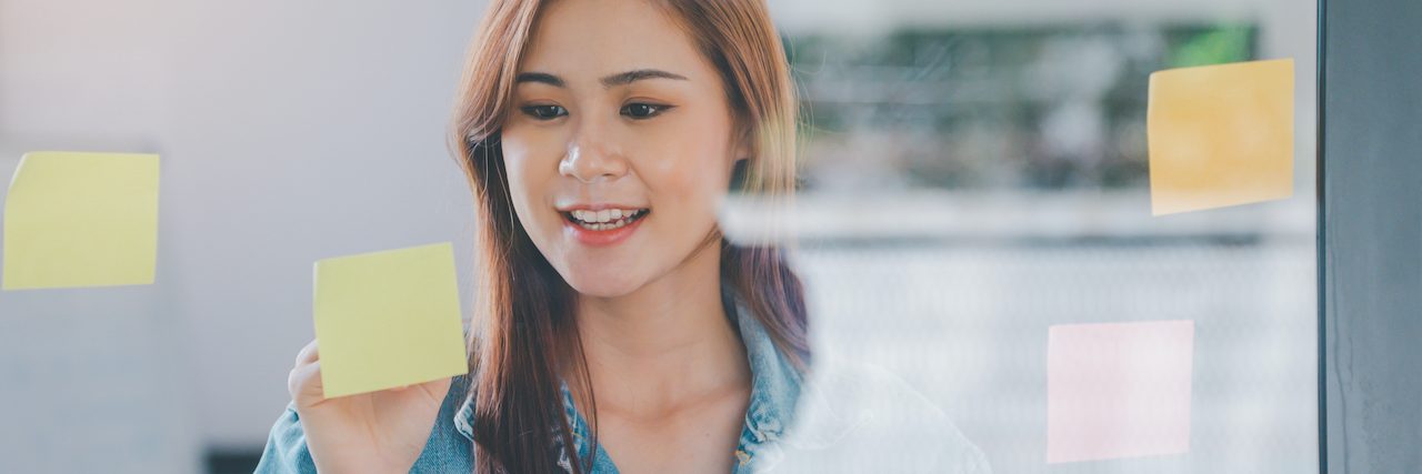 The Role of Object Permanence in ADHD Asian woman writing on sticky notes on clear board