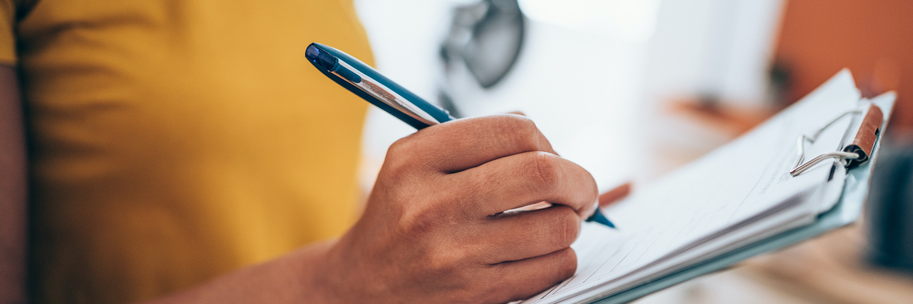 Cropped shot of an woman's hand making notes on a clipboard in an office