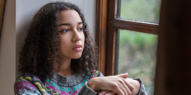 Beautiful mixed race teenager depressed or thoughtful looking out of a window